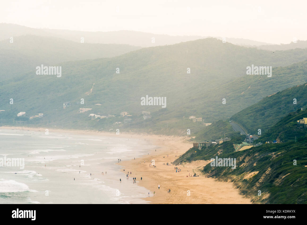 picturesque beach along the great ocean road in Australia. raised view of people walking along the beach with a glowing summer haze in the air Stock Photo