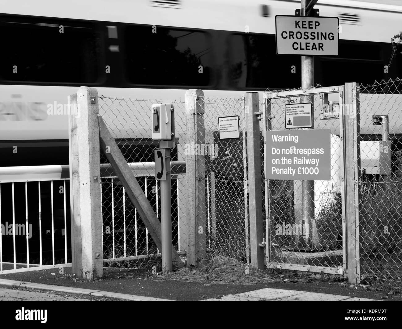 Rural railway level crossing with barriers down across roadway for train passing through Stock Photo