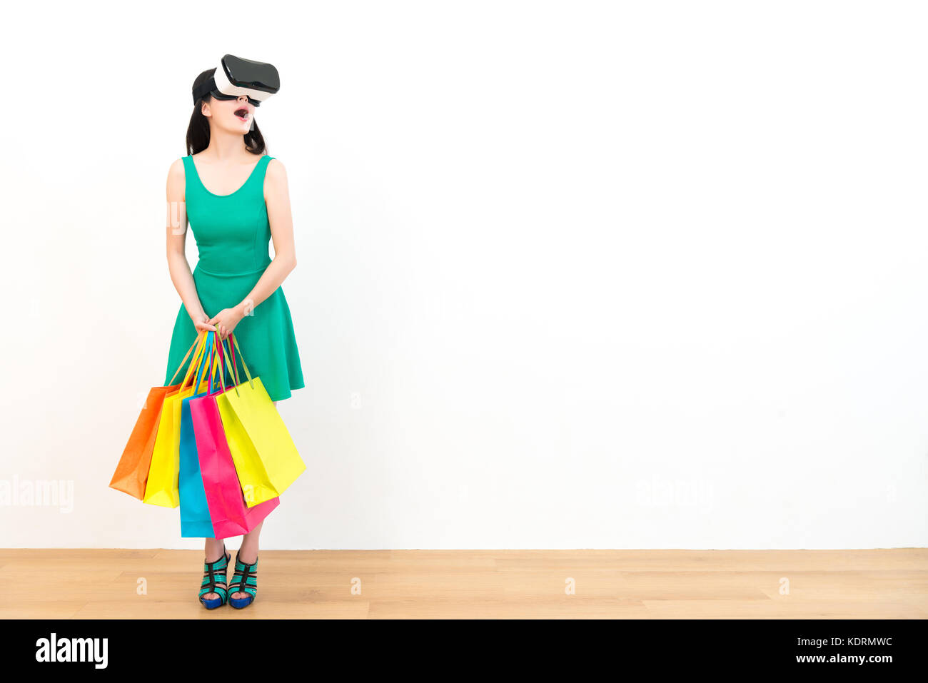 beauty lovely shopping girl wearing technology product virtual reality device viewing 3d video feeling surprised and standing in wooden floor with whi Stock Photo