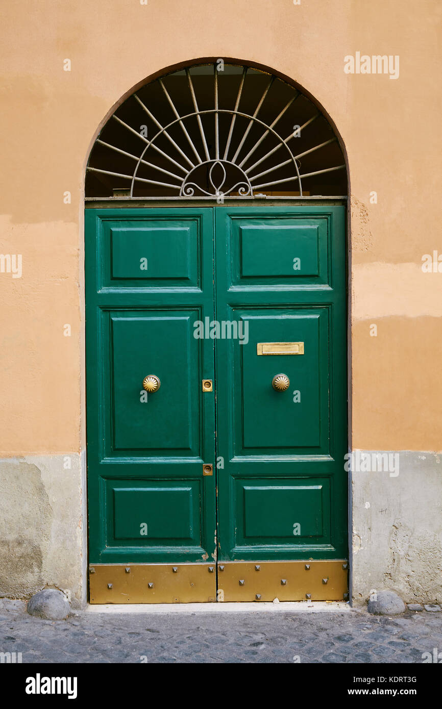 Old green door with golden handles in the old city in Rome Stock Photo