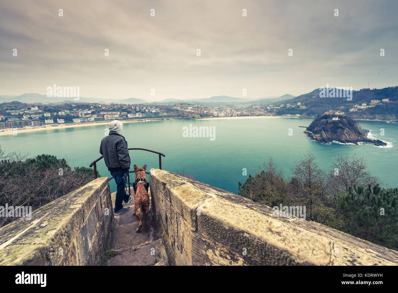 Man and german shepherd dog traveling together. Admiring view over San Sebastian in Spain. Stock Photo