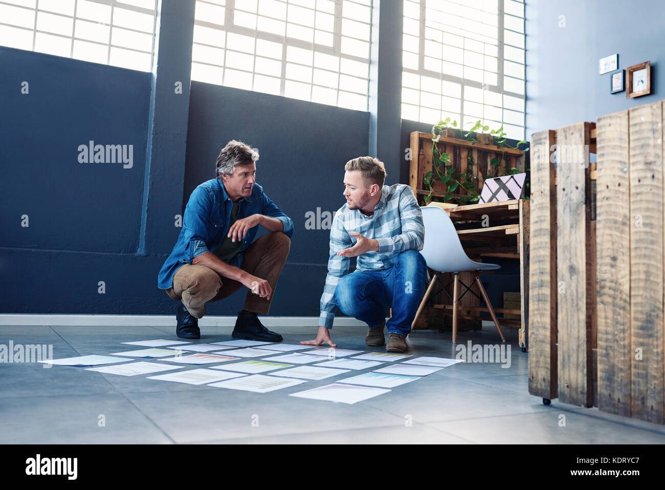 Two coworkers strategizing with papers on an office floor Stock Photo