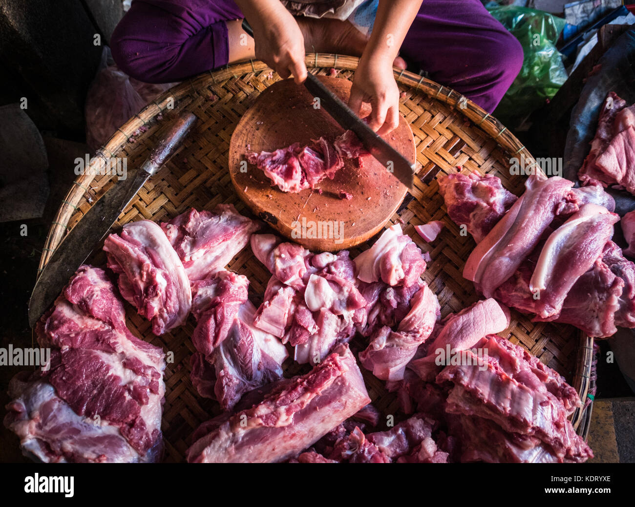 A female butcher cutting and preparing pork meat in Dong Ba Market, Hue, Vietnam Stock Photo