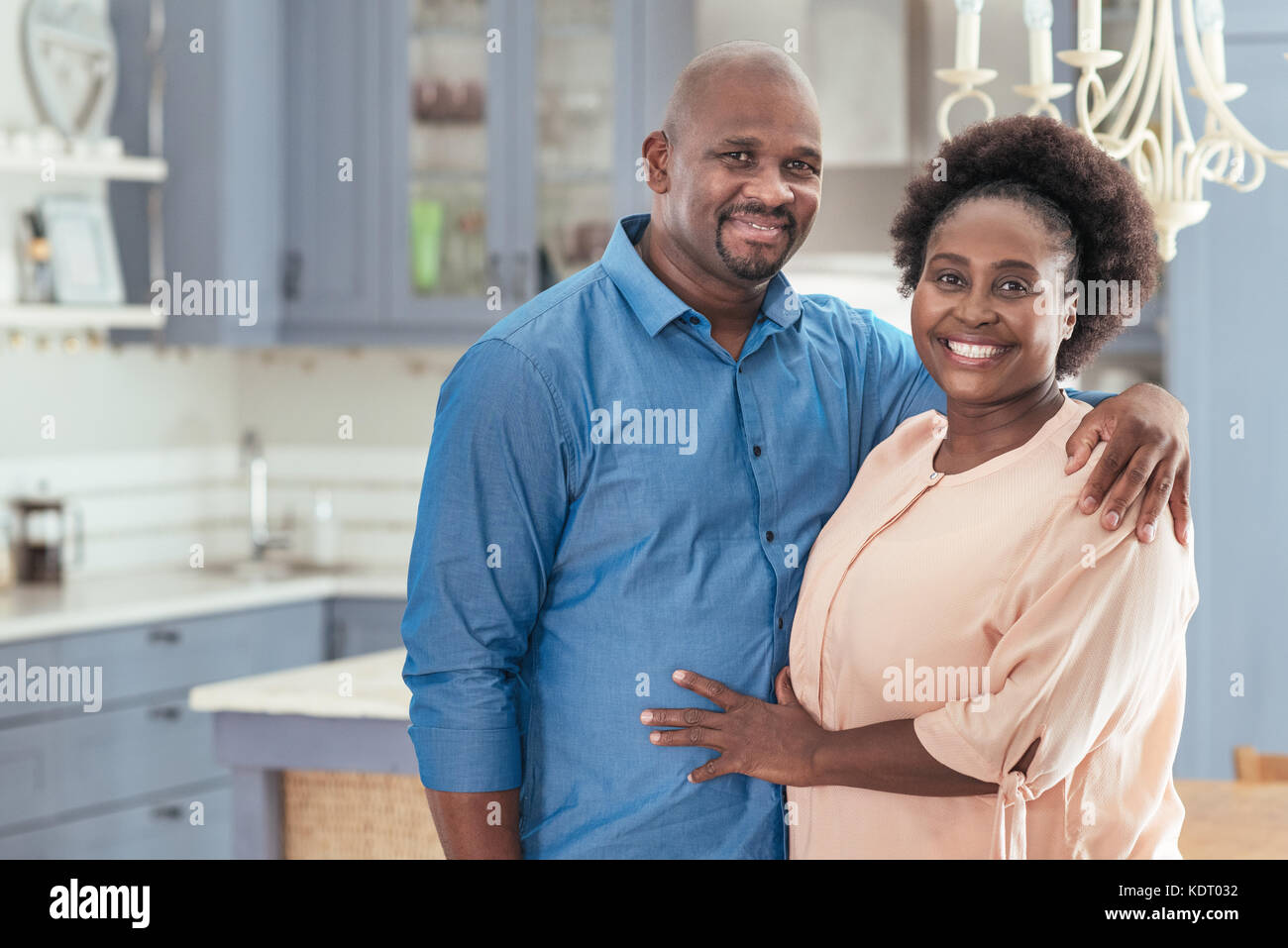 Affectionate African couple standing together in their kitchen Stock Photo