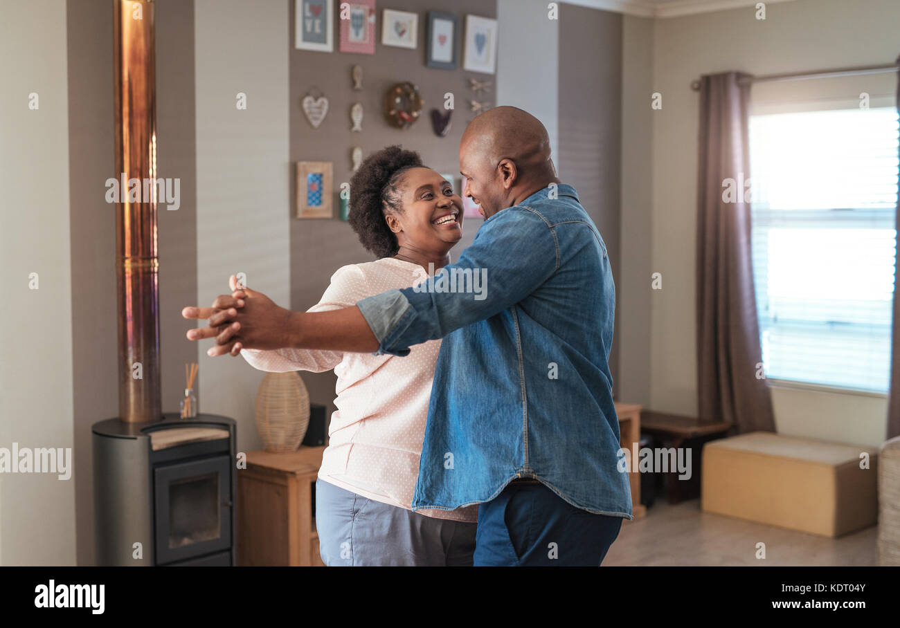 Smiling African couple dancing together in their living room Stock Photo