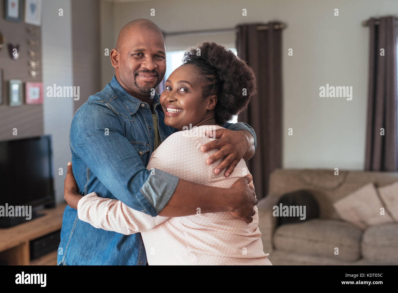 Affectionate African couple smiling and hugging each other at home Stock Photo