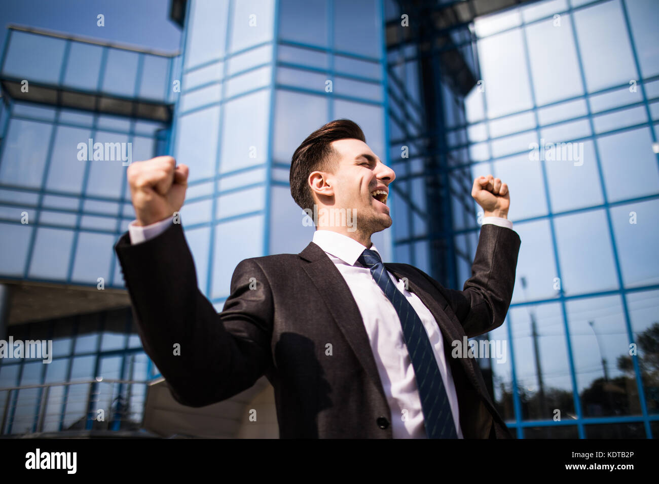 Celebrating success. Low angle view of excited young businessman ...