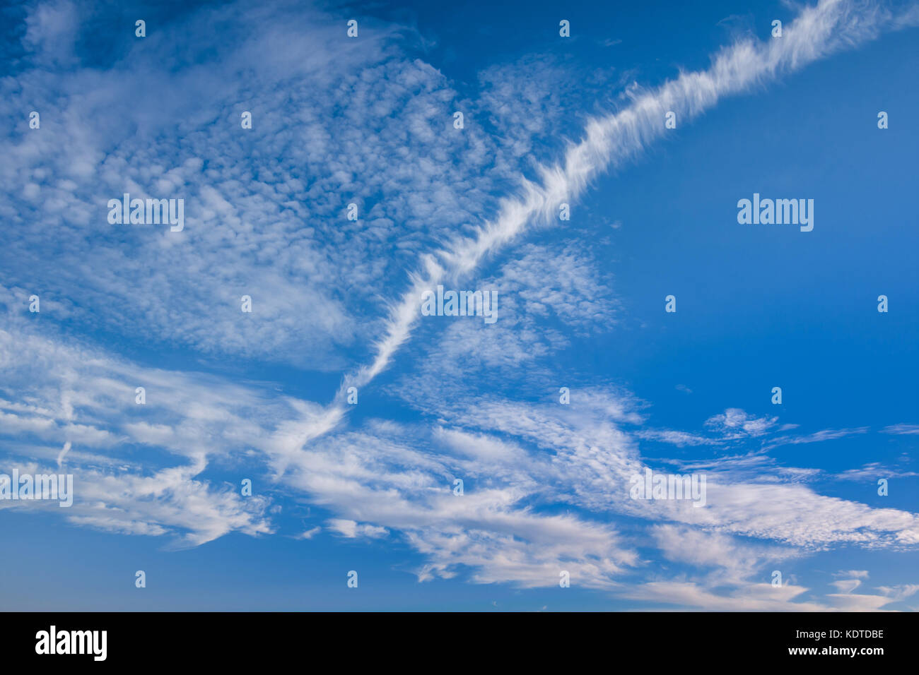 Contrail (or chemtrail) in cloudy sky - France. Stock Photo