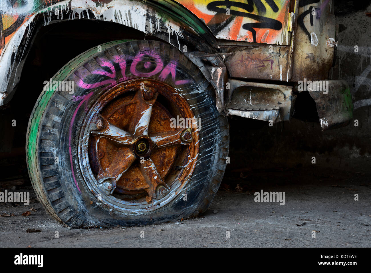 Abandoned spray painted vehicle with punctured tire Stock Photo