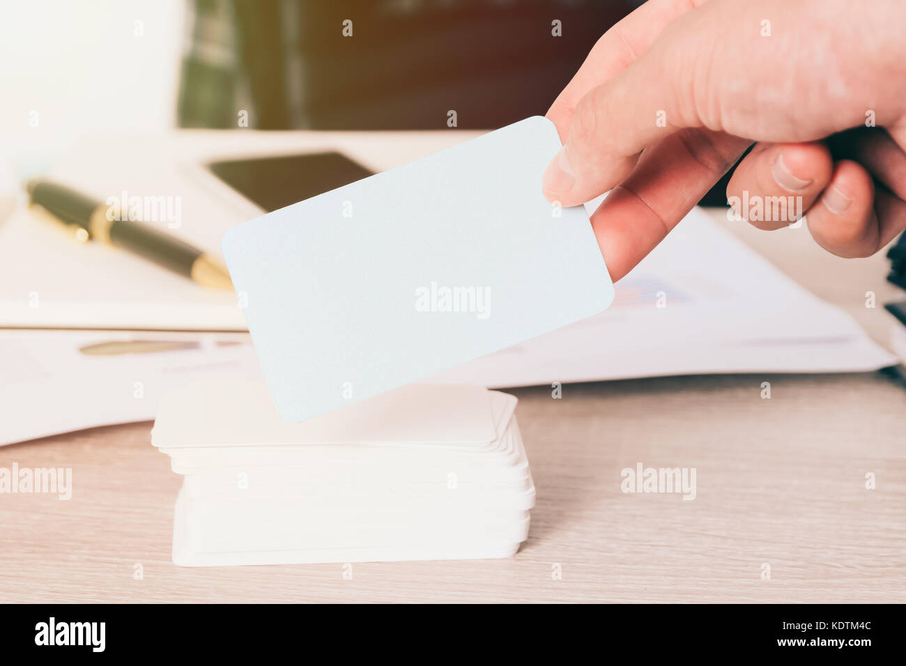 Blank Business Card In Hand On Blurred Office Desk Background Use