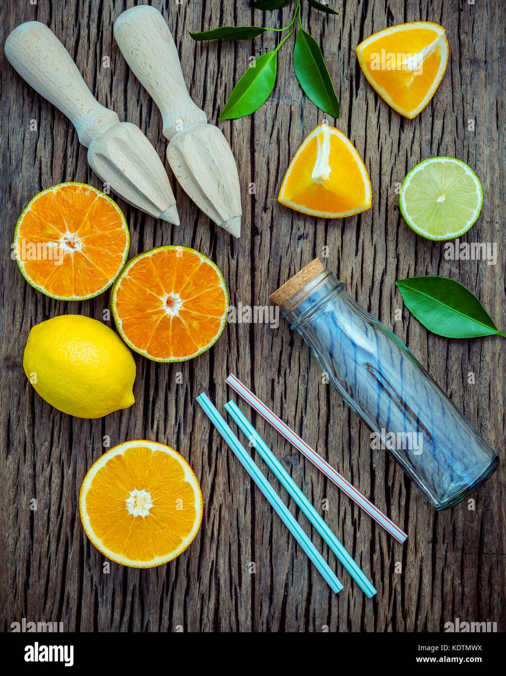 juice with juicer and glass bottle .Fresh lemons, lime and oranges set up on shabby wooden table with flat lay. Stock Photo