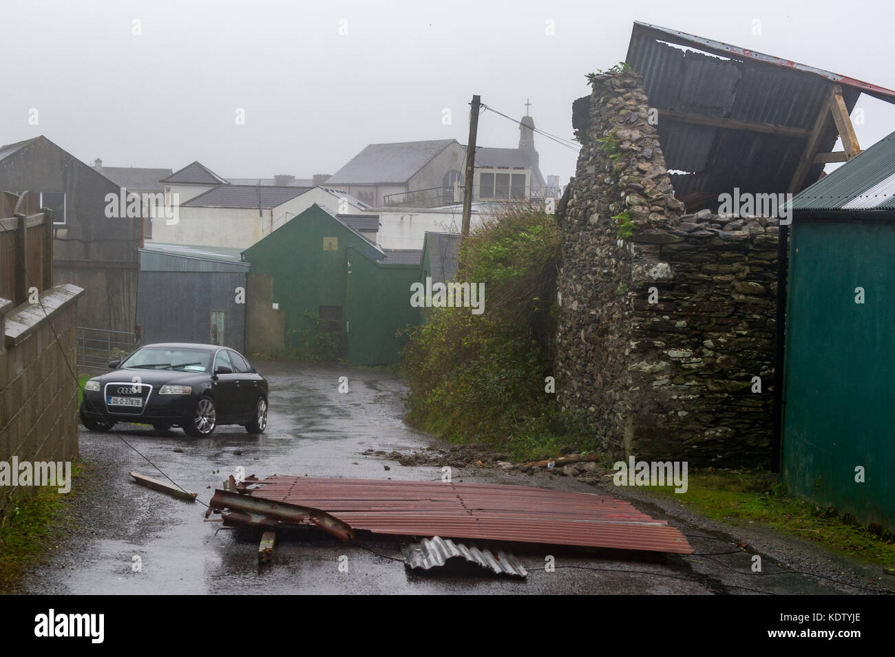 Schull, Ireland. 16th Oct, 2017. UK Weather.  Ex-Hurricane Ophelia hits Schull, Ireland with winds of 80kmh and gusts of 130kmh.  Major structural damage is expected as the worst is yet to come. A tin roof blocks the entrance and exit to Centra in Schull. Credit: Andy Gibson/Alamy Live News. Stock Photo