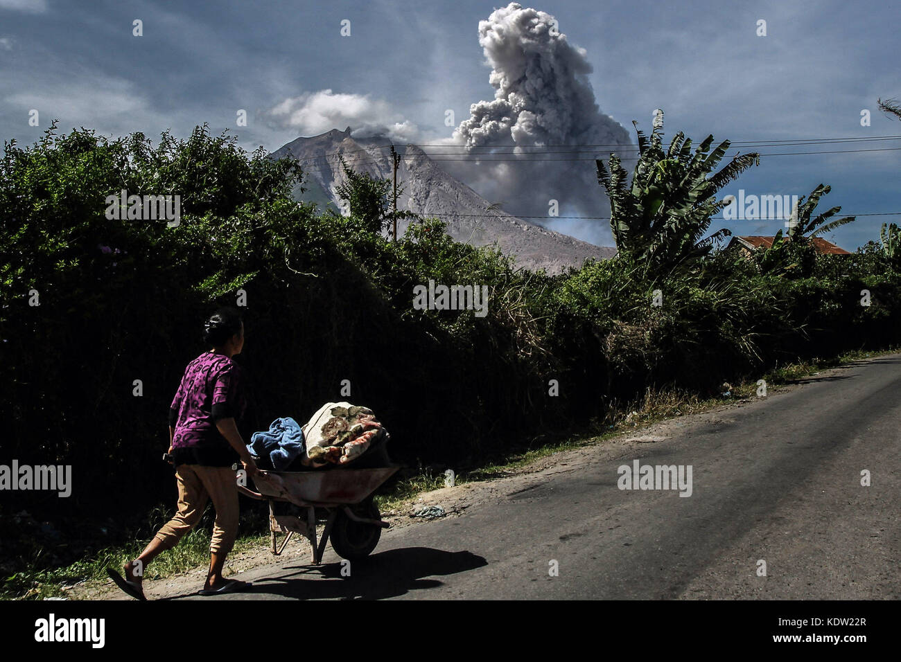 Karo, North Sumatra, Indonesia. 16th Oct, 2017. The villagers of Tiga Pancur walk near the volcano of Mount Sinabung which spewed dust as seen in Karo, North Sumatera province, on 16 October 2017. A huge volcano in Indonesia erupted on Sunday, spewing hot ash into the air. Thousands were evacuated after Mount Sinabung started erupting and spewing ash half a kilometre into the air. The volcano began erupting in 2010 after lying dormant for four centuries. A large eruption in May 2016 killed seven people. Credit: Ivan Damanik/ZUMA Wire/Alamy Live News Stock Photo