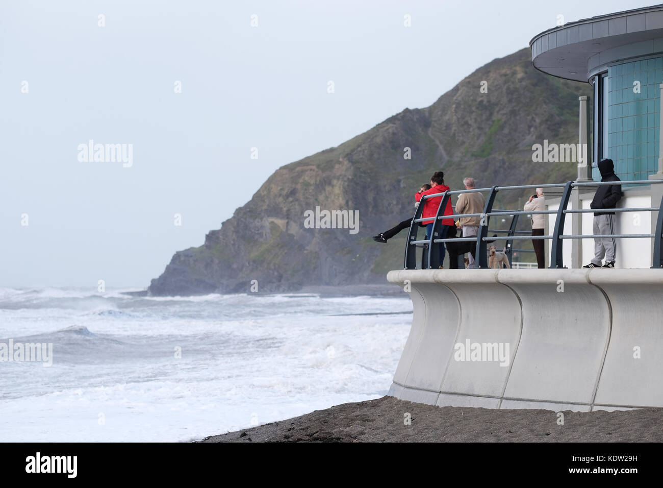 Aberystwyth, Ceredigion, Wales, UK  - 4pm People begin to gather to as high tide approaches ( due approx 18.30 ) at the town beach - strong winds at Aberystwyth on the West Wales coast as Storm Ophelia approaches off the Irish Sea with local winds exceeding 50mph. Photo Steven May / Alamy Live News Stock Photo