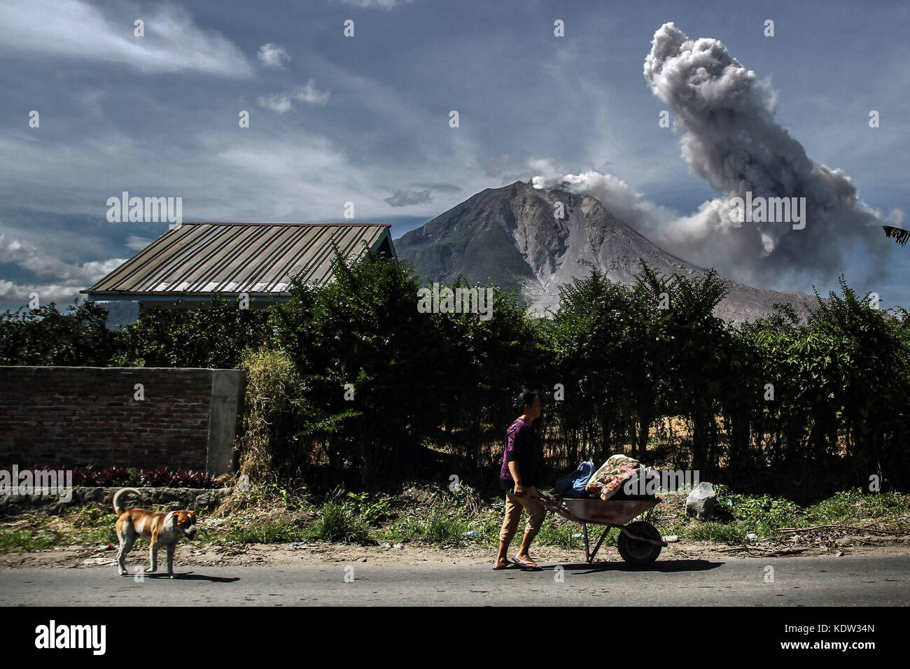 Karo, North Sumatra, Indonesia. 16th Oct, 2017. The villagers of Tiga Pancur walk near the volcano of Mount Sinabung which spewed dust as seen in Karo, North Sumatera province. Thousands were evacuated after Mount Sinabung started erupting and spewing ash half a kilometre into the air. The volcano began erupting in 2010 after lying dormant for four centuries. A large eruption in May 2016 killed seven people. Credit: Ivan Damanik/ZUMA Wire/Alamy Live News Stock Photo
