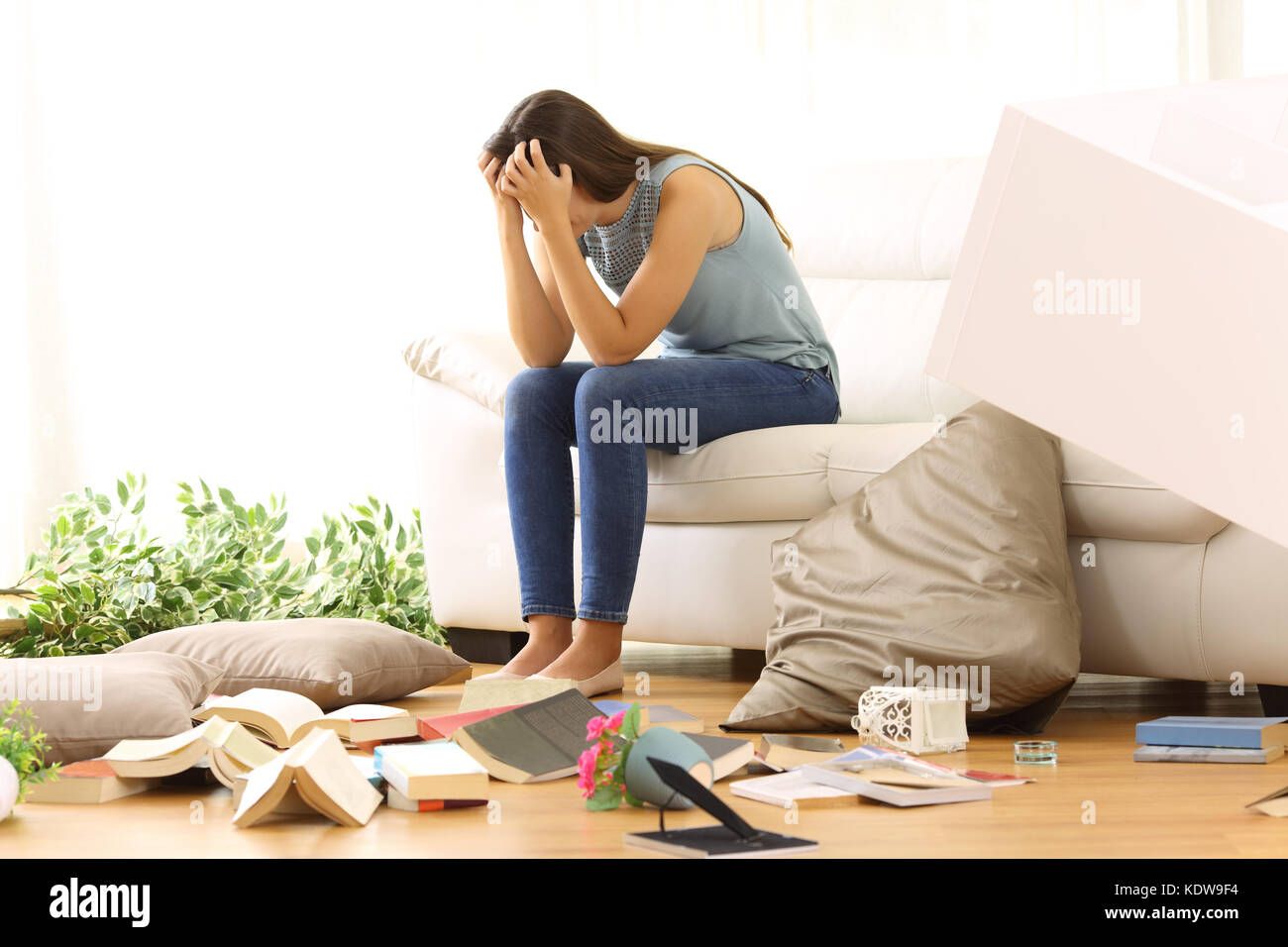 Desperate homeowner complaining after home robbery sitting on a couch of the messy living room at home Stock Photo