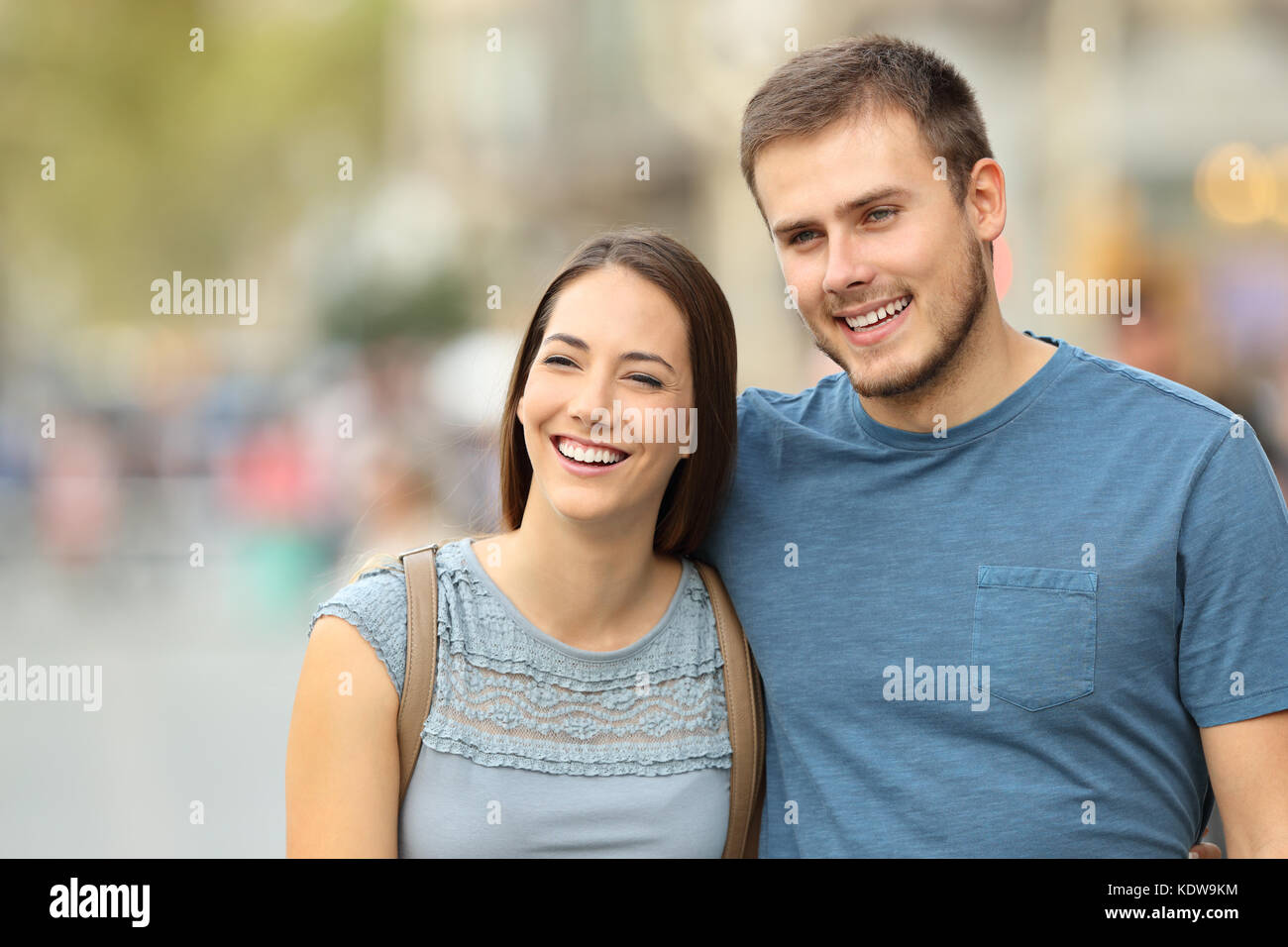 Front view of a happy couple walking on the street and looking away Stock Photo