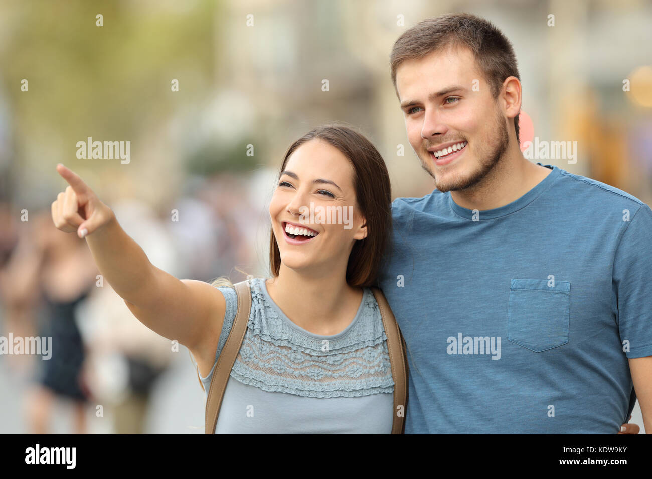 Happy couple finding location and pointing at side walking on the street Stock Photo