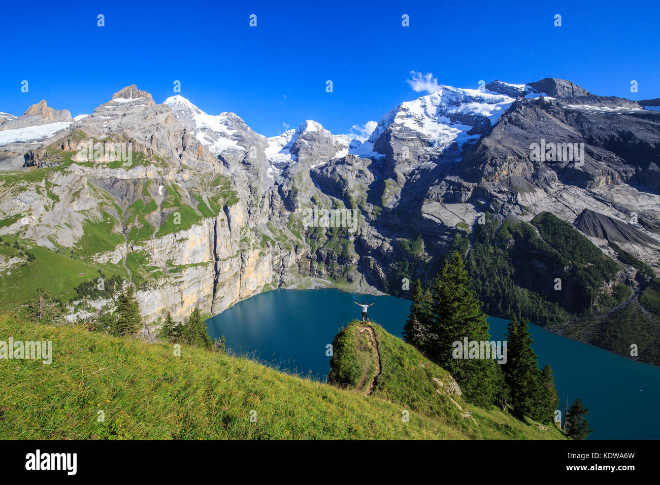 Hiker admires Lake  Oeschinensee Bernese Oberland Kandersteg Canton of Bern Switzerland Europe Stock Photo