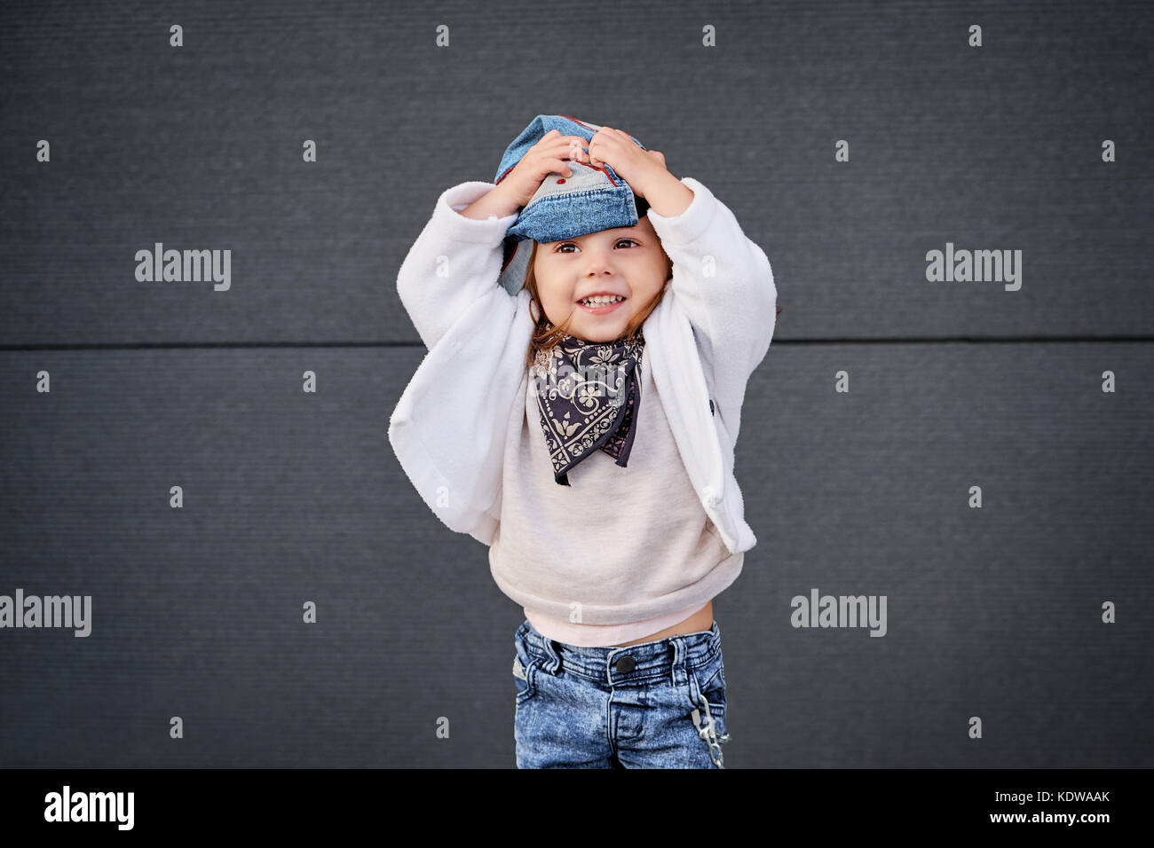 model child hip-hop.little baby girl in the baseball cap happy dancing in the background of the gray wall.Children's fashion. Stock Photo