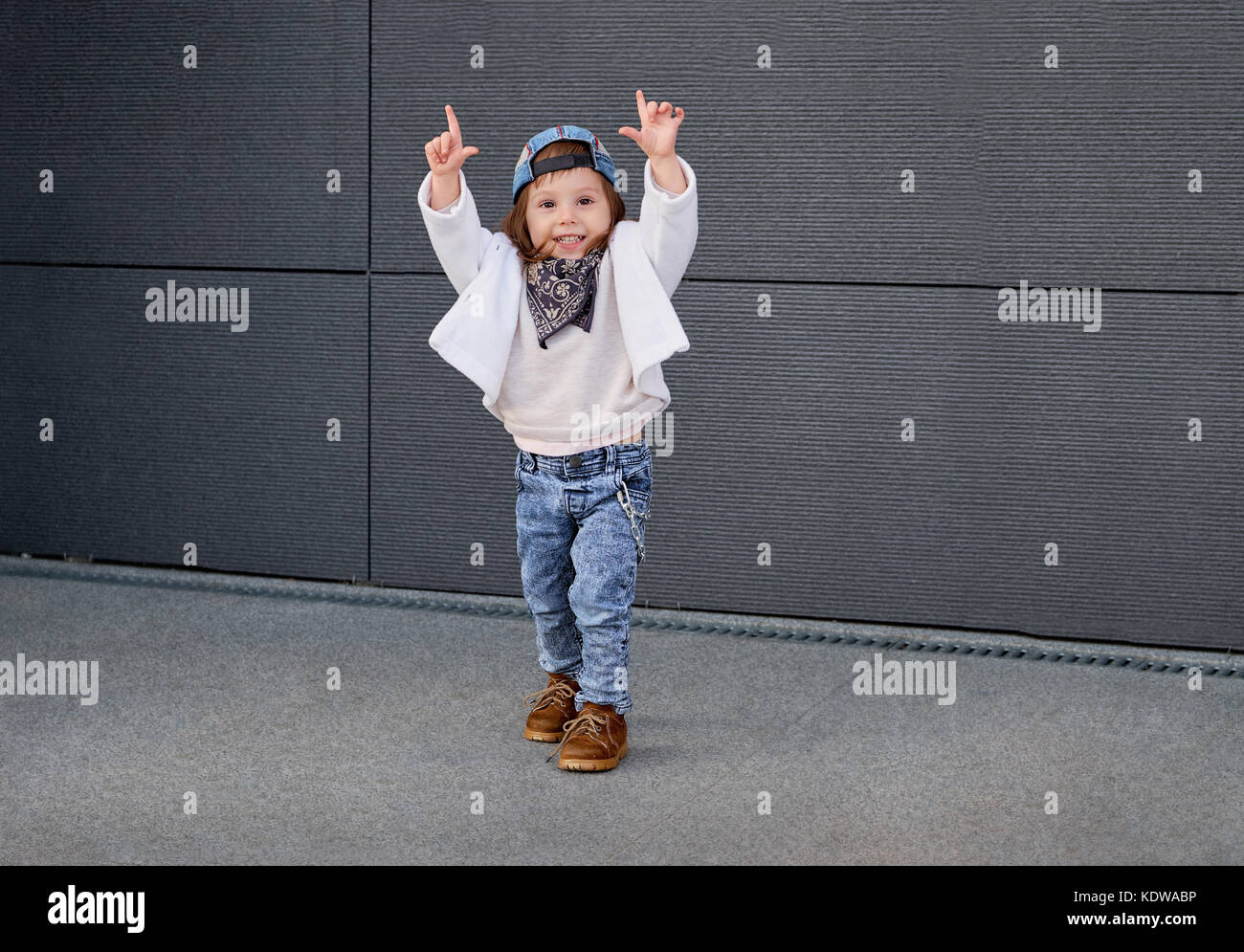 fashion baby girl hip hop.Portrait of a cute little girl in fashionable clothes.little baby girl in the baseball cap happy dancing in the background o Stock Photo