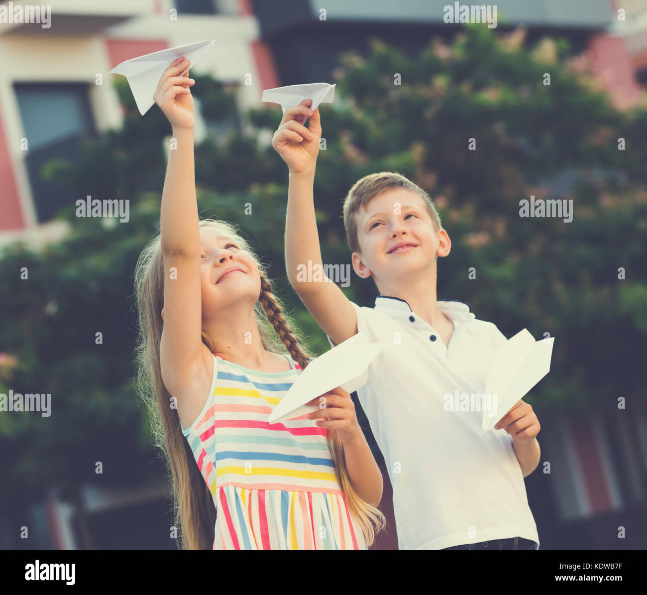 Two smiling kids playing with flying paper planes outdoors Stock Photo ...