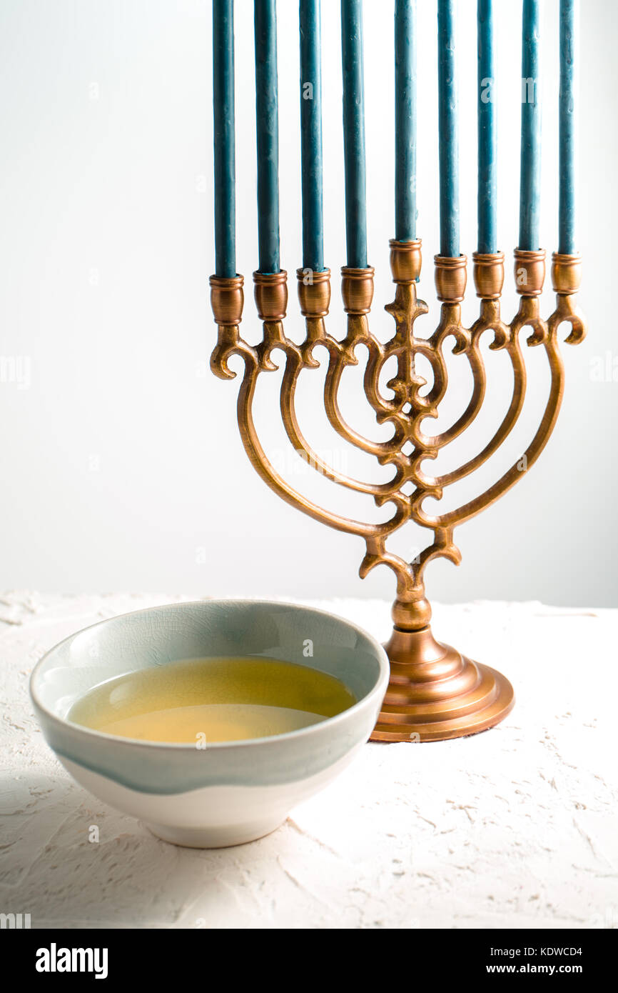 Menorah brass Hanukkah with blue candles and butter in bowl side view vertical Stock Photo