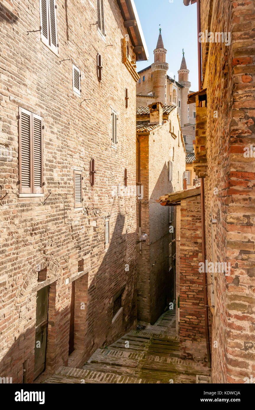 The renaissance town of Urbino, Marche, Italy. A view of the Ducale Palace (Palazzo Ducale) seen from a narrow street in Urbino city, Marche, Italy Stock Photo