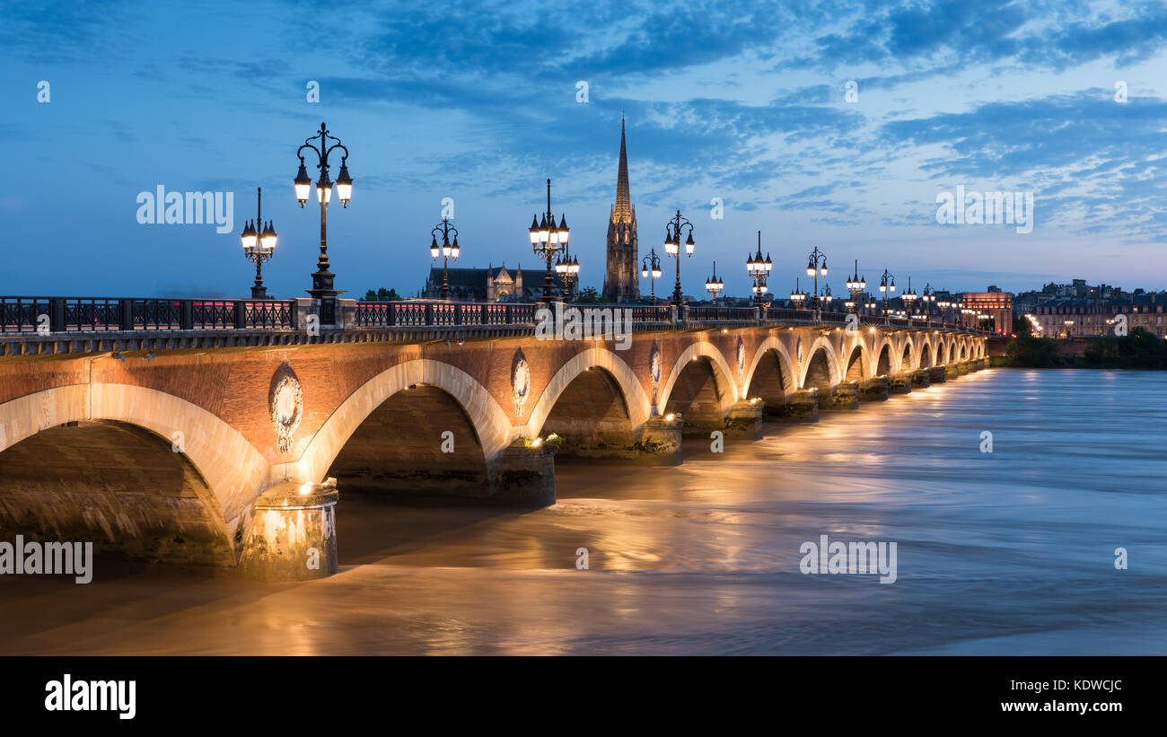 Pont de Pierre spanning the River Garonne at dusk with Basilique Saint-Michel beyond, Bordeaux, Aquitaine, France Stock Photo
