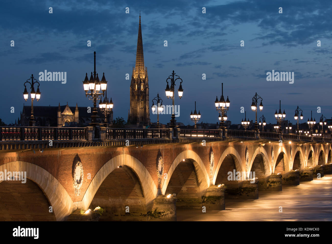 Pont de Pierre spanning the River Garonne at dusk with Basilique Saint-Michel beyond, Bordeaux, Aquitaine, France Stock Photo
