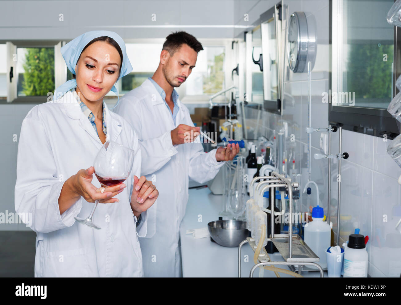 Positive Researcher Two young efficient smiling positive researchers in white coat checking ...