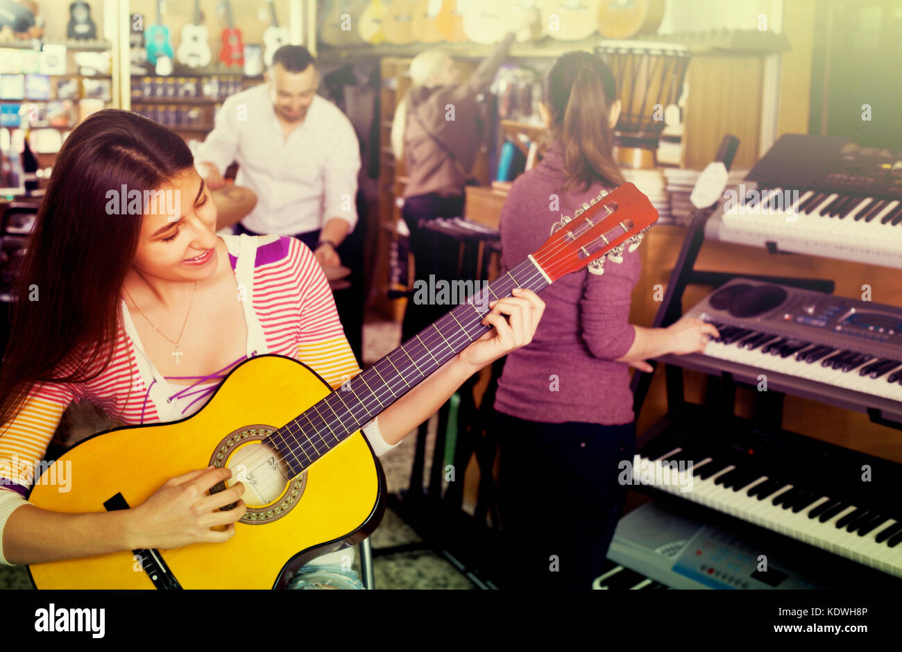 Smiling people looking at professional musical instruments in store ...