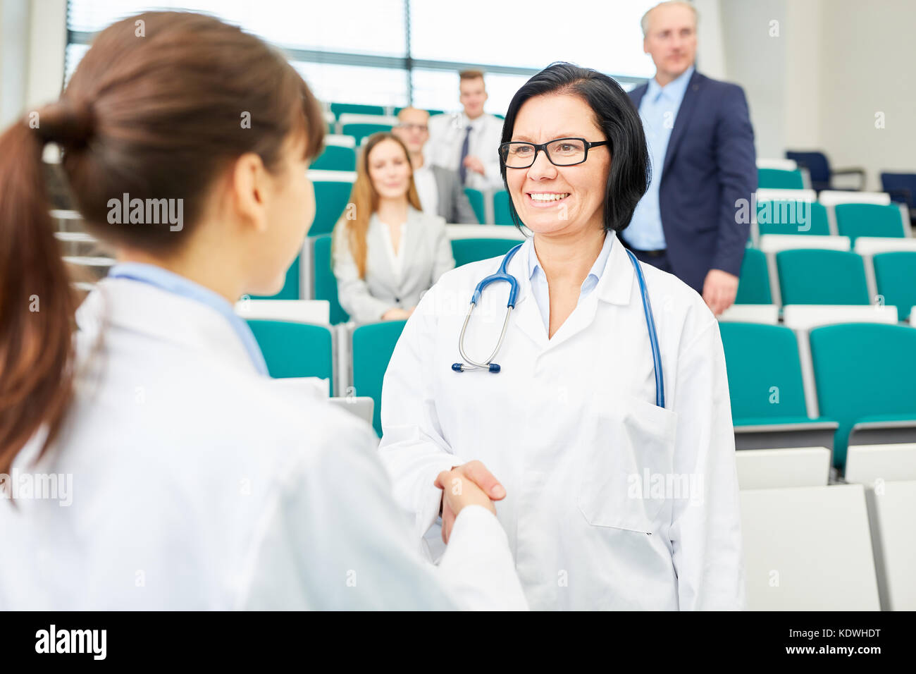 Doctors congratulate woman with handshake for successful career test results Stock Photo