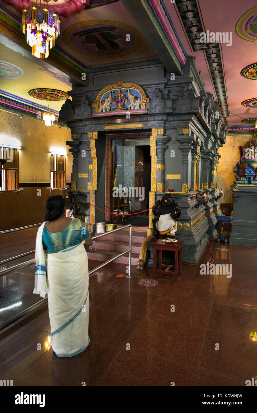 The Seychelles, Mahe, Victoria, Quincy Street, Sri Navasakthi Vinayagar Hindu temple interior, worshipper at inner sanctum Stock Photo