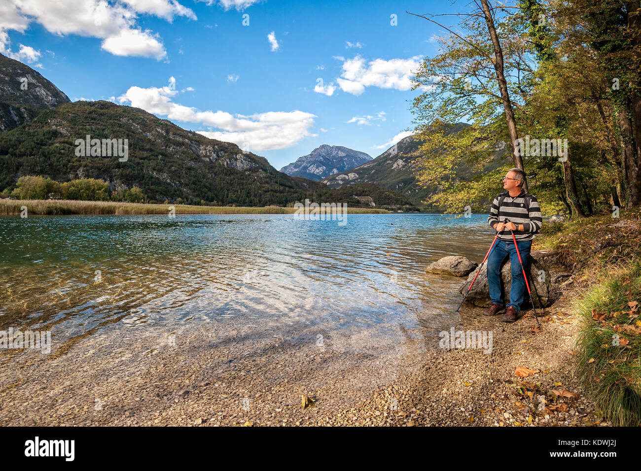 Hiker sitting on a boulder at the lake shore. Tramper admires the panorama Stock Photo