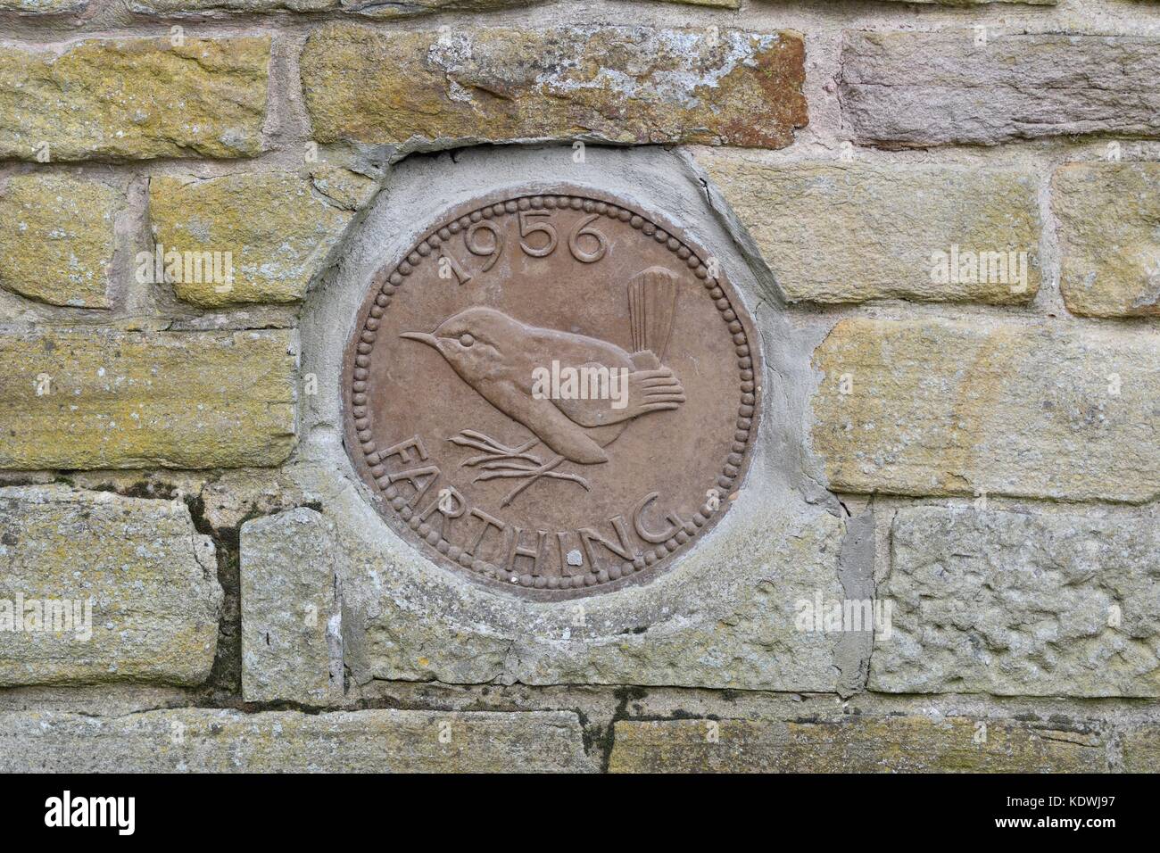 A giant farthing is built into the wall of a house in New Mills, Derbyshire Stock Photo