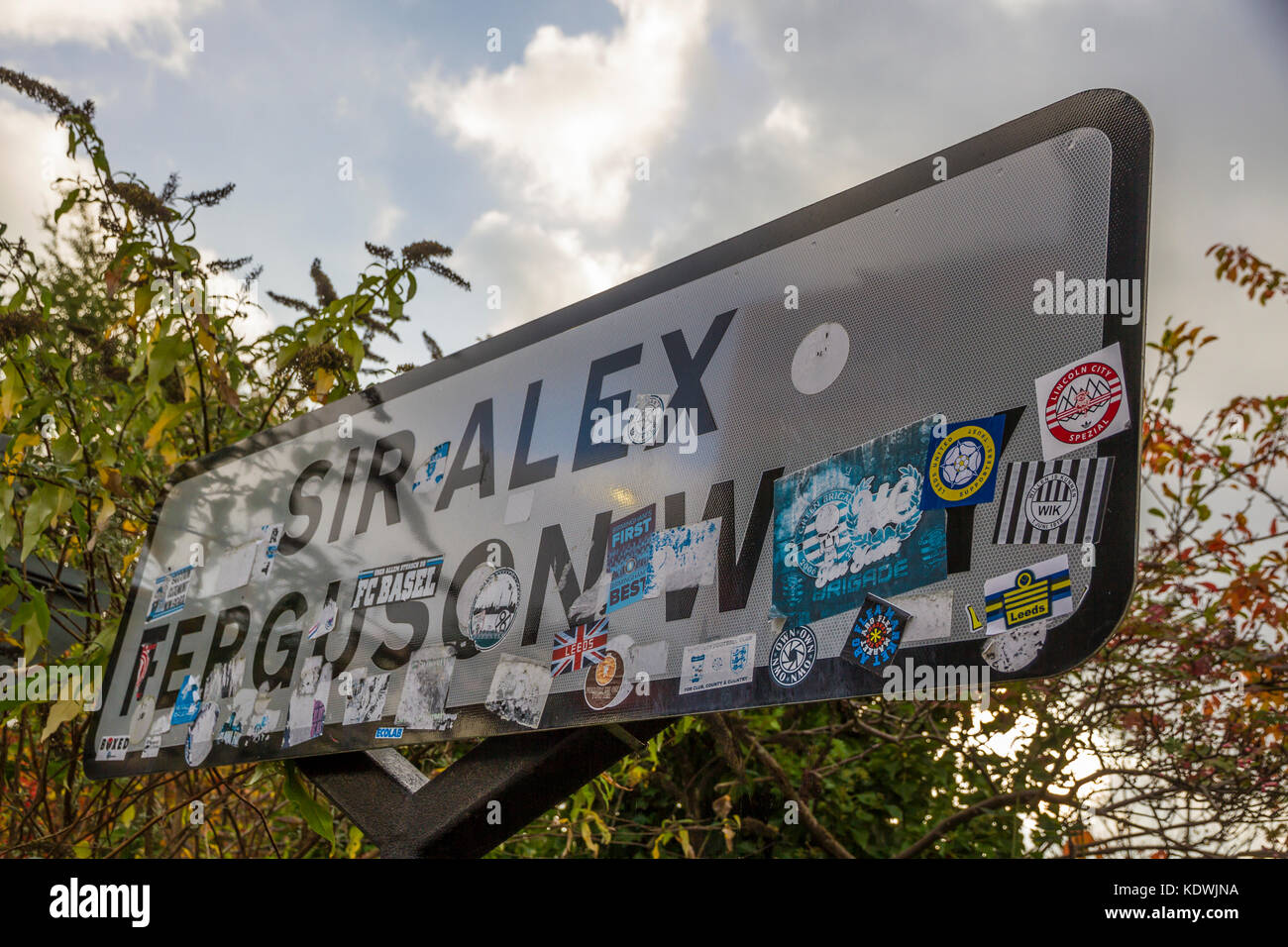 Footbll Stickers on the Sir Alex Ferguson Way Road Sign near Old Trafford Football Stadium. Stock Photo