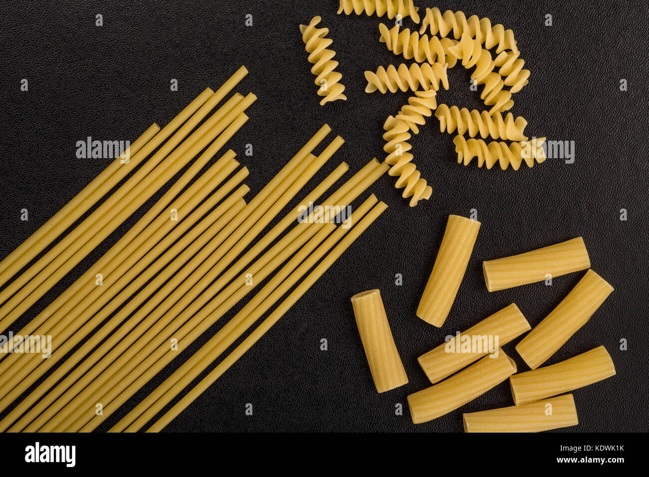 Selection of Raw Uncooked Italian Style Pasta Spaghetti Rigatoni and Fusilli With Copy Space On A Black Background Stock Photo