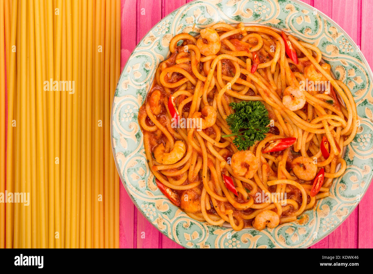 Italian Style Spicy Prawn or Shrimp Spaghetti In A Chilli Tomato Sauce On A Pink Wooden Background Stock Photo
