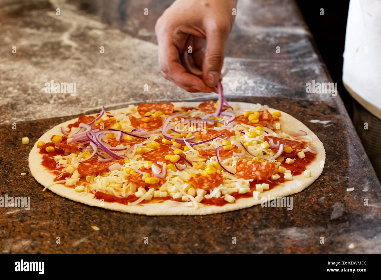 Cook's hands putting red onion on tomato base pizza Stock Photo Alamy
