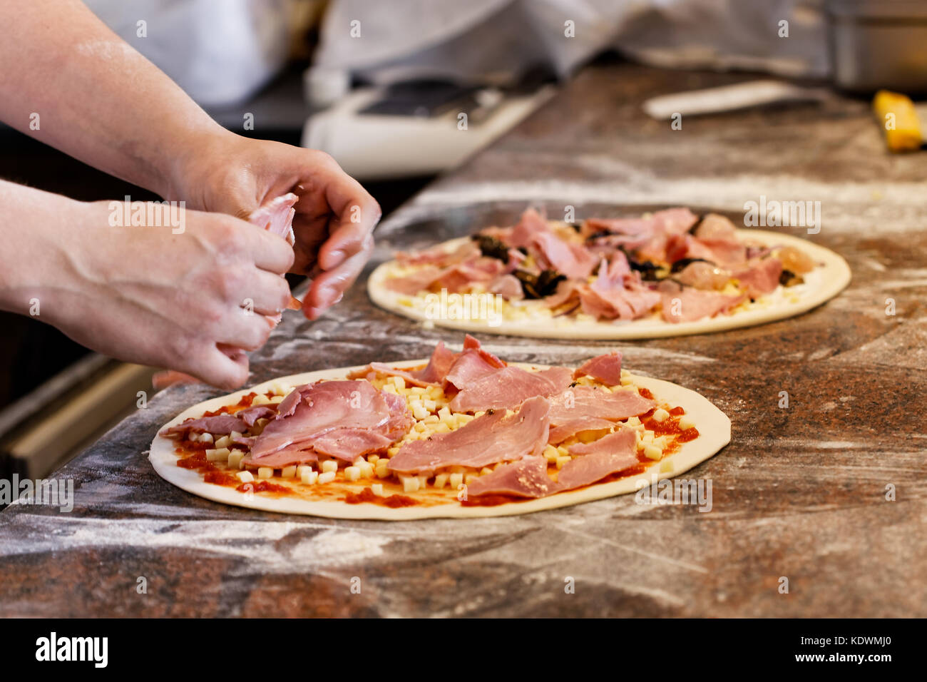 Cook putting toppings on two pizzas Stock Photo Alamy