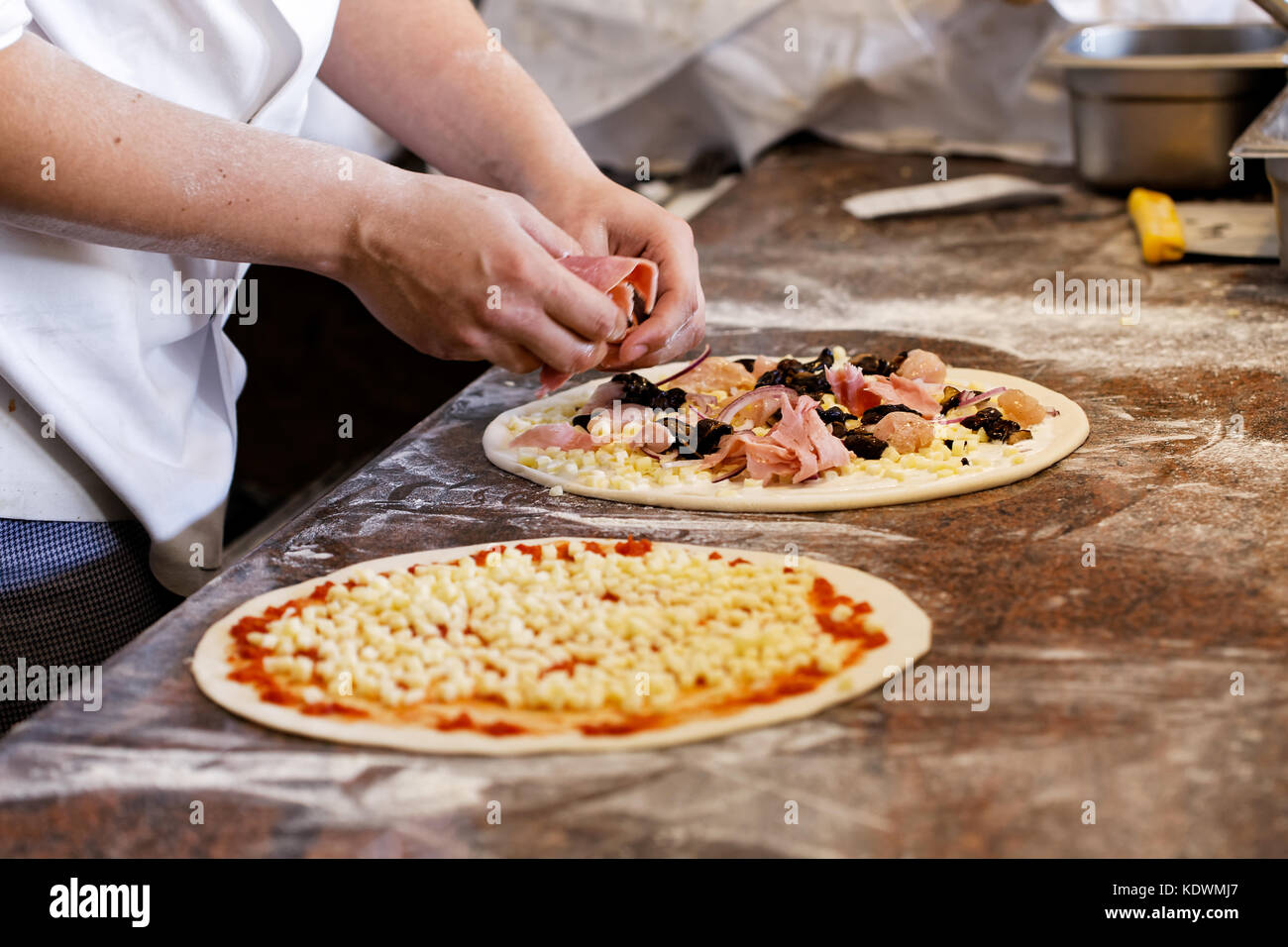 Cook putting toppings on two pizzas Stock Photo Alamy