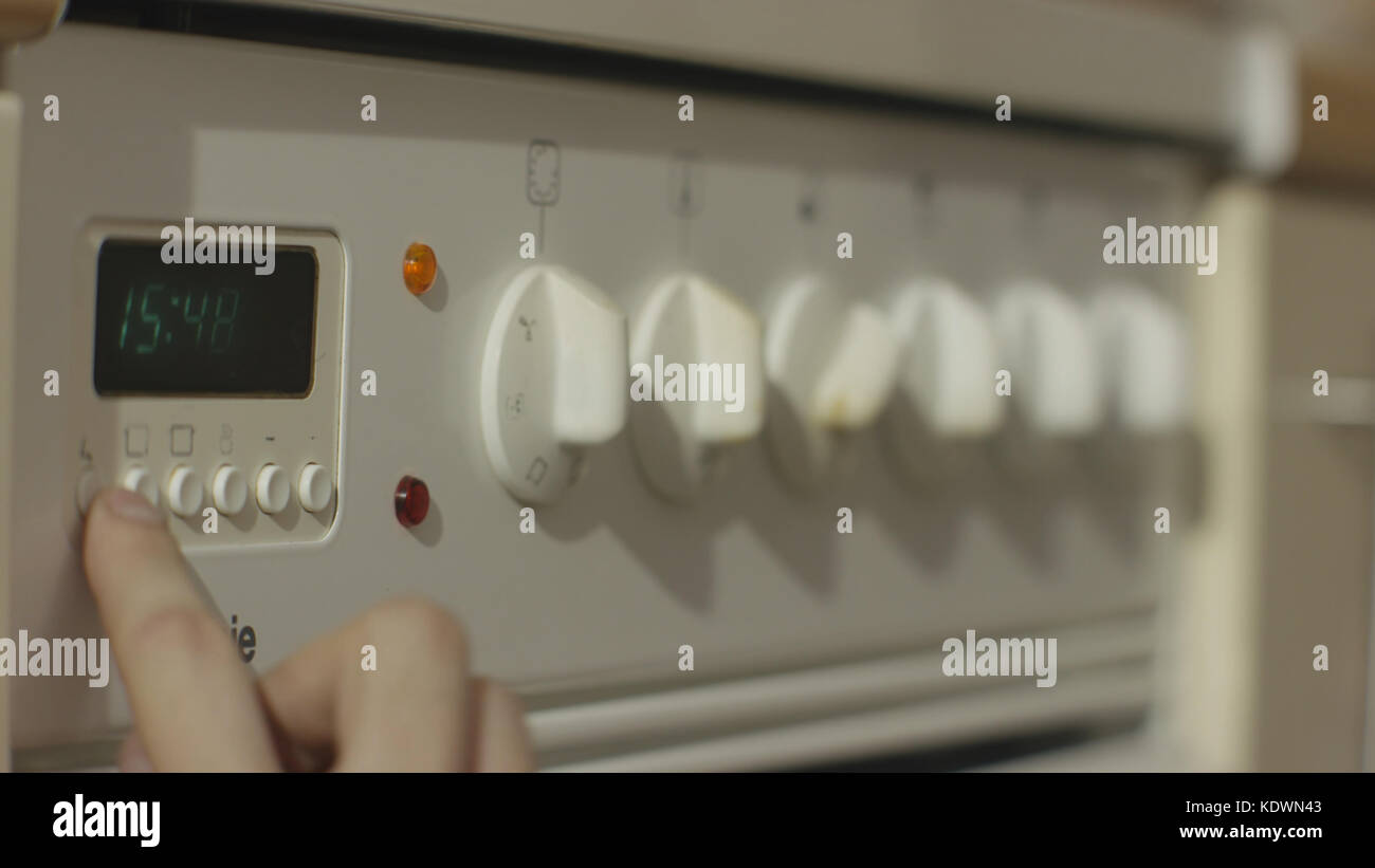 Female hand turning on white kitchen gas stove. Woman turn on the stove