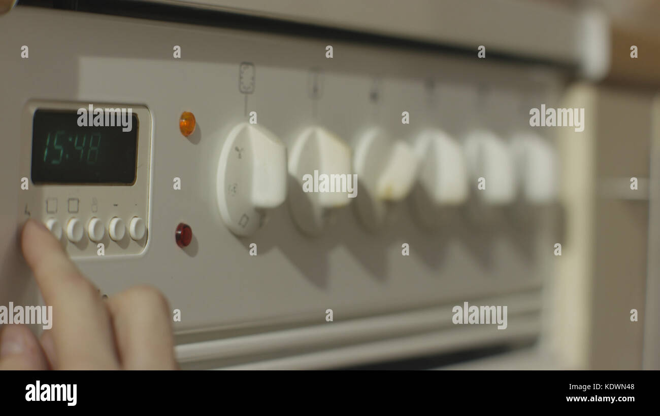 Female hand turning on white kitchen gas stove. Woman turn on the stove