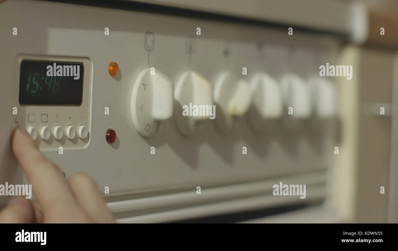 Female hand turning on white kitchen gas stove. Woman turn on the stove in the kitchen close up