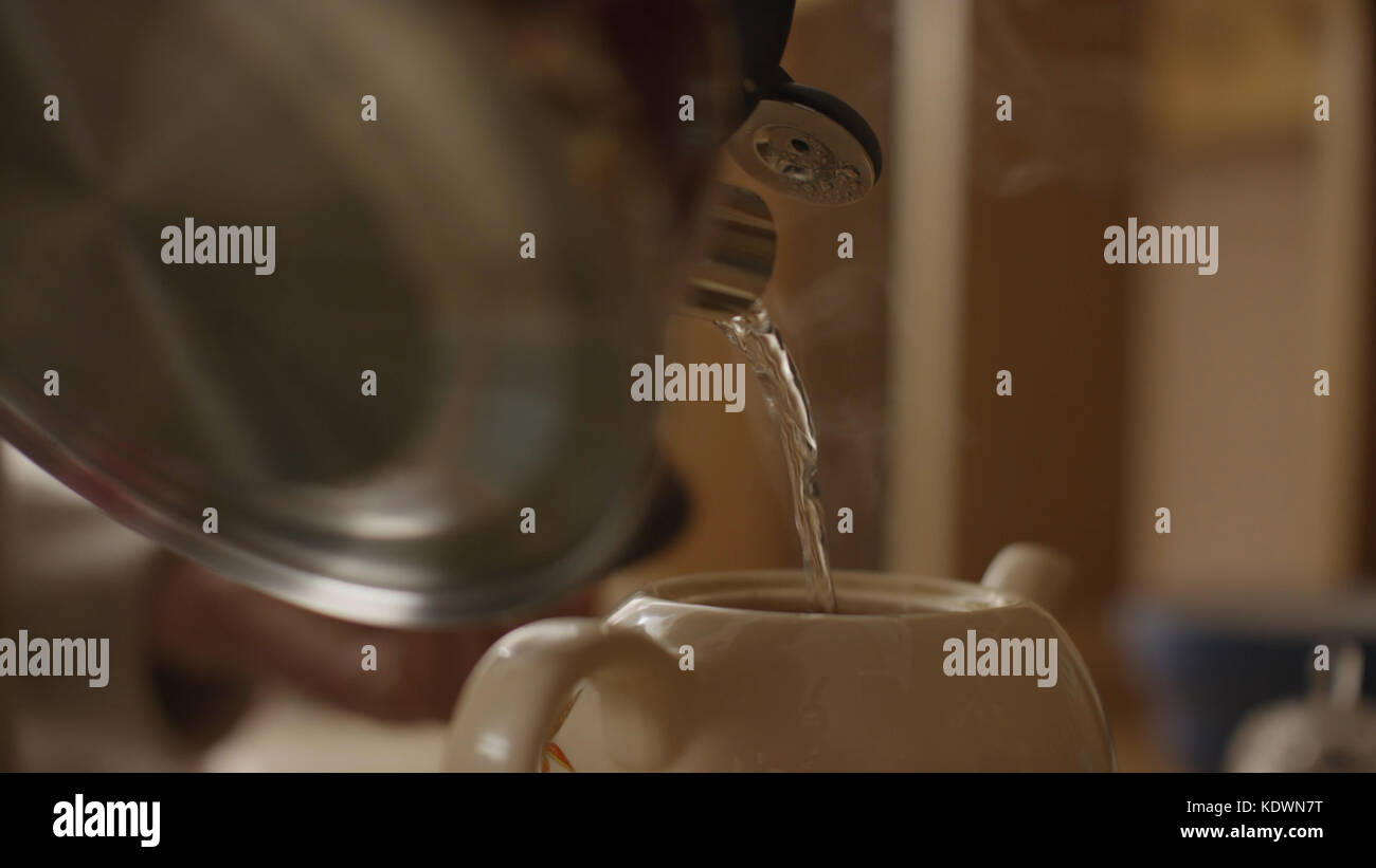 Woman pours boiling water into the cup and brew tea in a tea bag. The woman pours hot water into
