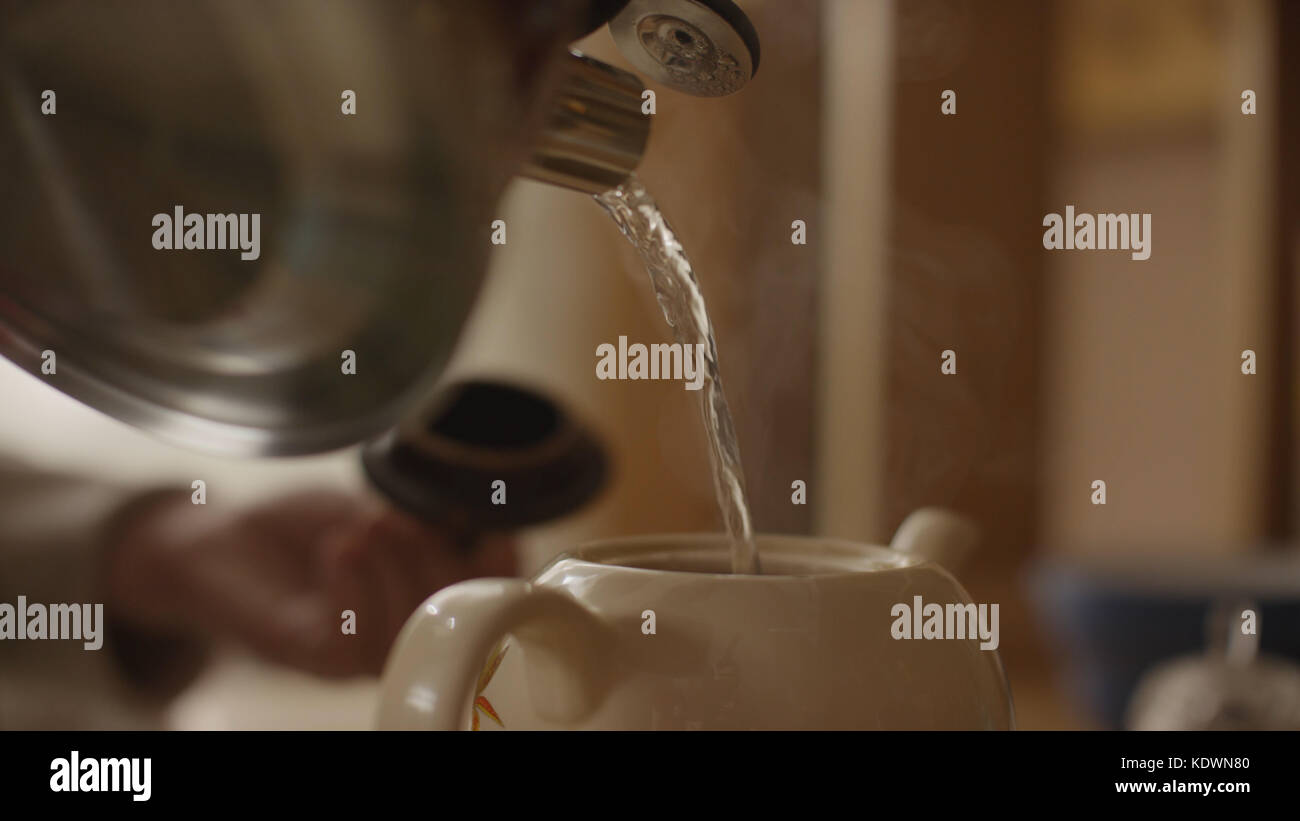 Woman pours boiling water into the cup and brew tea in a tea bag. The woman pours hot water into
