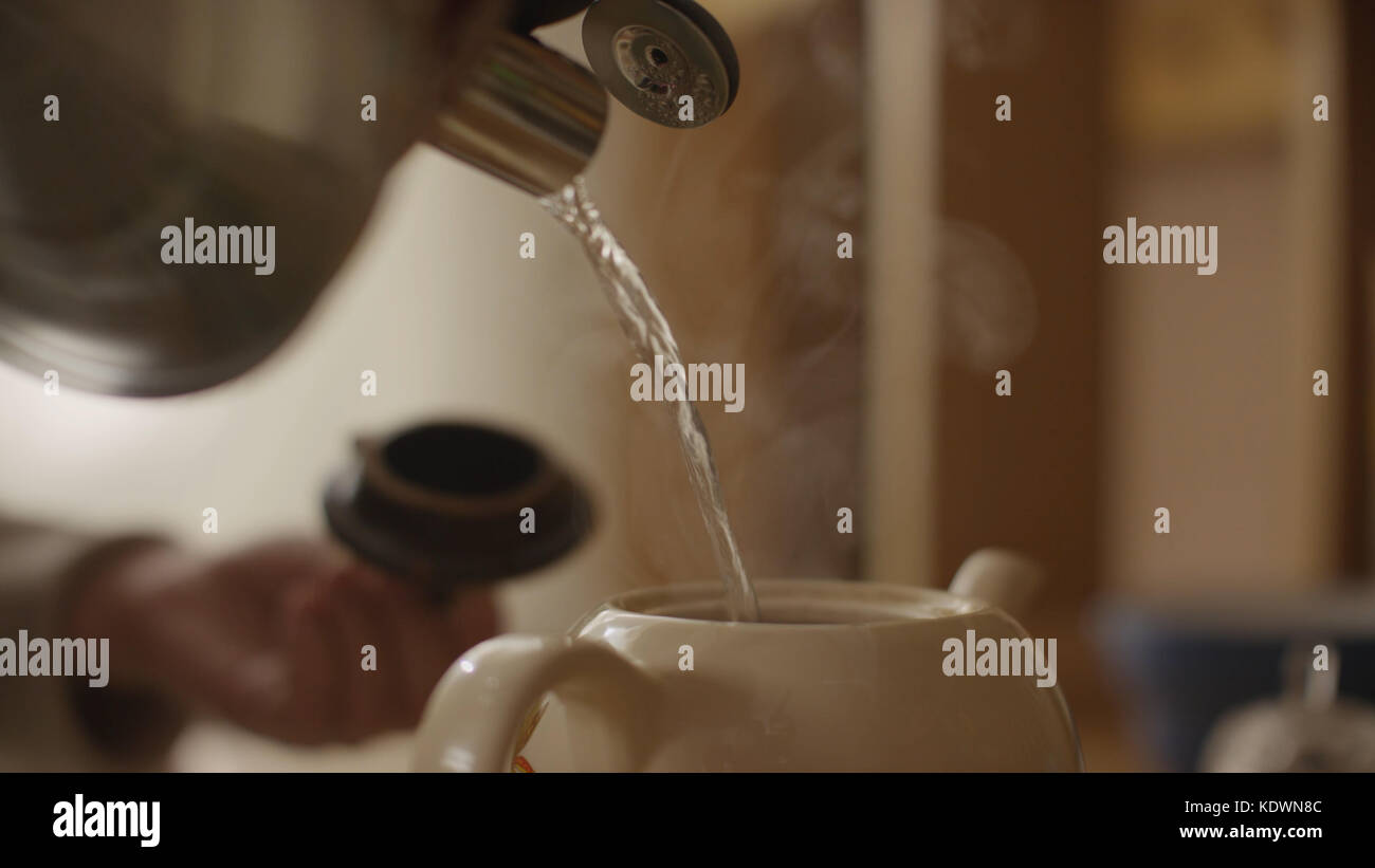 Woman pours boiling water into the cup and brew tea in a tea bag. The