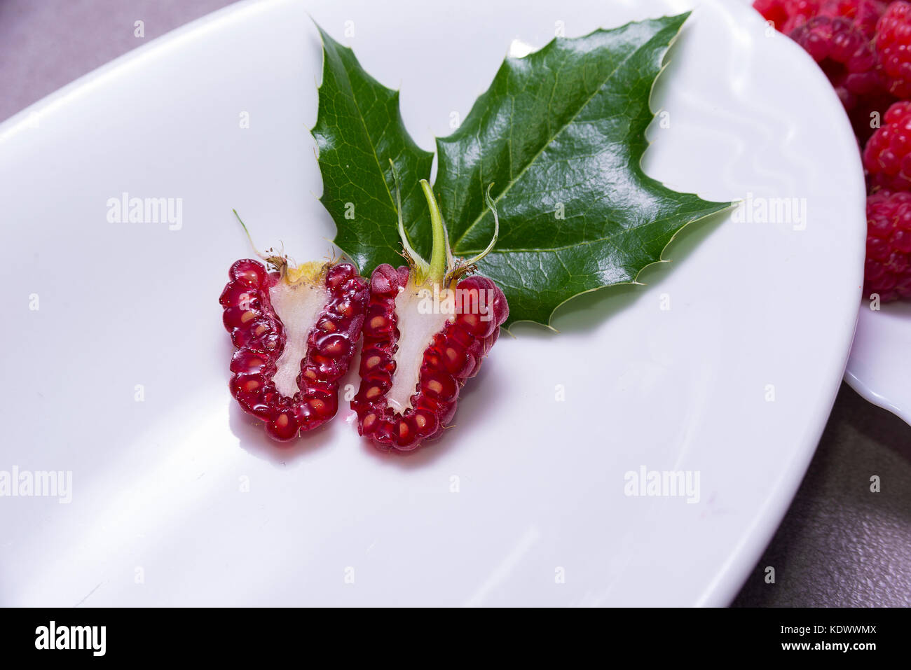 Raspberry cut in half on the plate with the leaf Stock Photo Alamy