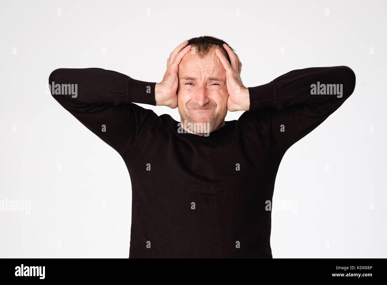 Mature spanish man closing his ears because of headache or migraine Stock Photo